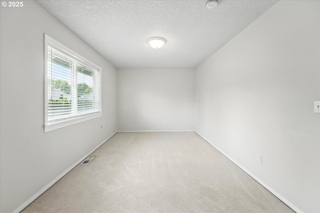 carpeted empty room with baseboards, a textured ceiling, and a smoke detector