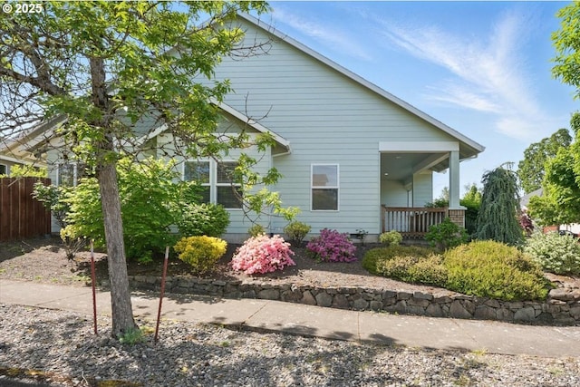 view of side of property featuring covered porch and fence