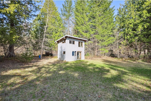view of green lawn with an outbuilding and a view of trees