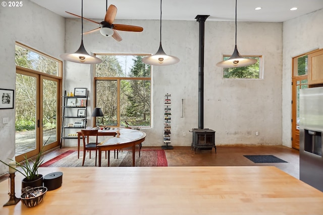dining room with a wood stove, a high ceiling, and a ceiling fan