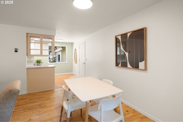 dining space with light wood-type flooring and baseboards