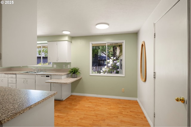 kitchen featuring dishwasher, a sink, white cabinetry, and plenty of natural light