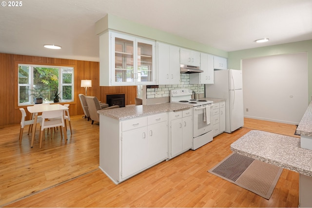 kitchen featuring white appliances, under cabinet range hood, light countertops, decorative backsplash, and white cabinetry