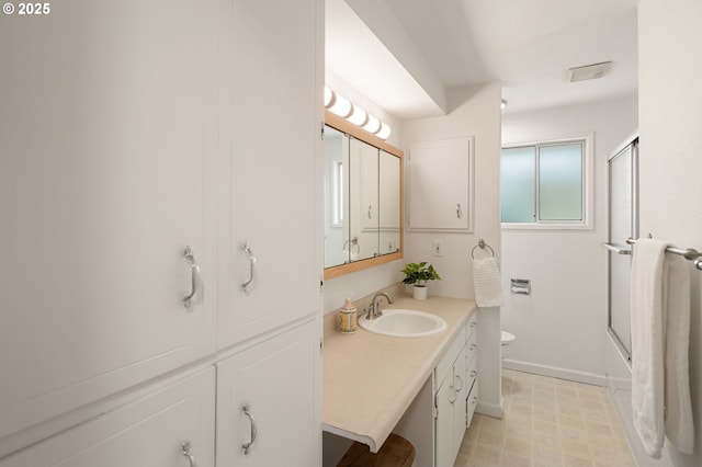 bathroom featuring baseboards, toilet, vanity, shower / bath combination with glass door, and tile patterned floors