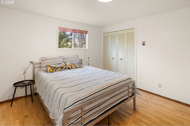 bedroom featuring baseboards, light wood finished floors, and a closet