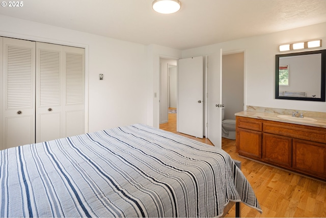 bedroom with a sink, light wood-type flooring, and a closet