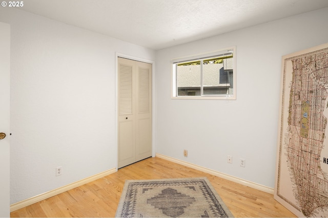 unfurnished bedroom with light wood finished floors, baseboards, and a closet