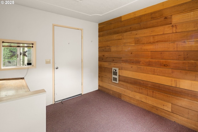 spare room featuring wood walls and dark carpet