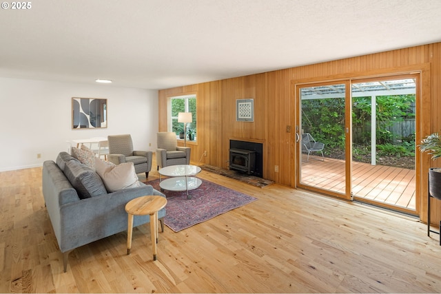 living area featuring plenty of natural light, wood finished floors, a wood stove, wood walls, and baseboards