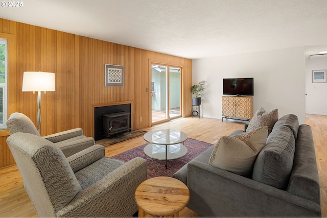living area featuring a wood stove, wood finished floors, baseboards, and wood walls