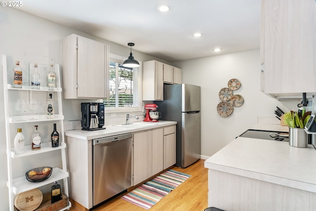 kitchen featuring appliances with stainless steel finishes, a sink, light countertops, recessed lighting, and light wood-style flooring