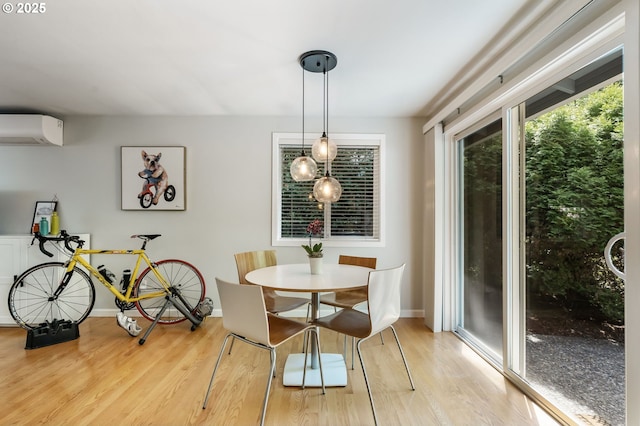 dining area with an AC wall unit, light wood-type flooring, and baseboards