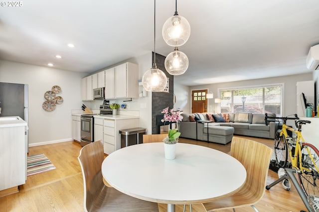dining area with light wood-style floors, recessed lighting, baseboards, and a wall mounted AC