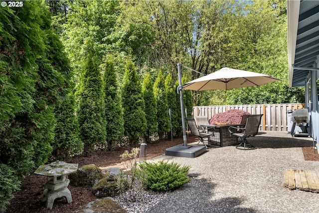 view of patio / terrace featuring outdoor dining area, grilling area, and a view of trees