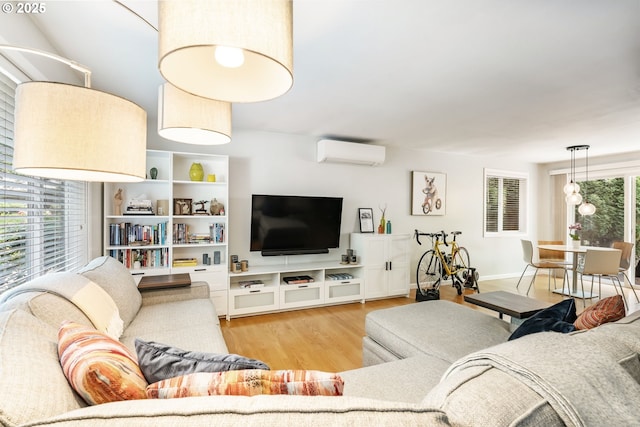 living room featuring an AC wall unit, wood finished floors, and baseboards