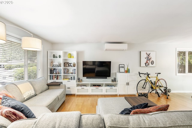 living area with wood finished floors, a wall unit AC, and baseboards