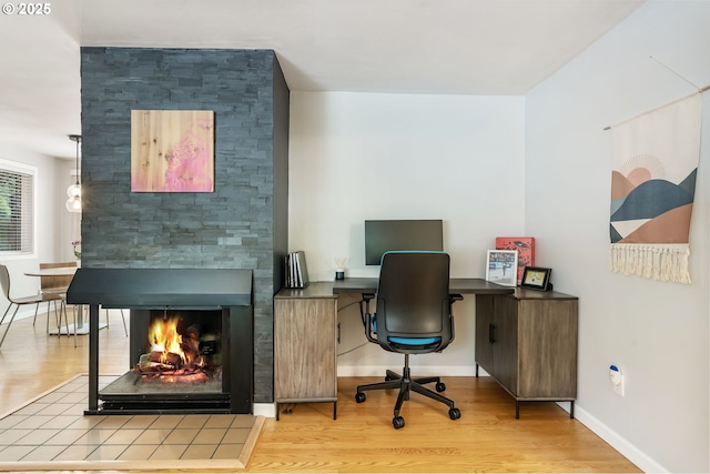 office featuring wood finished floors, a multi sided fireplace, and baseboards