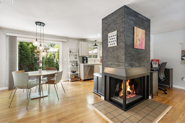 dining area featuring light wood-type flooring, a multi sided fireplace, and baseboards