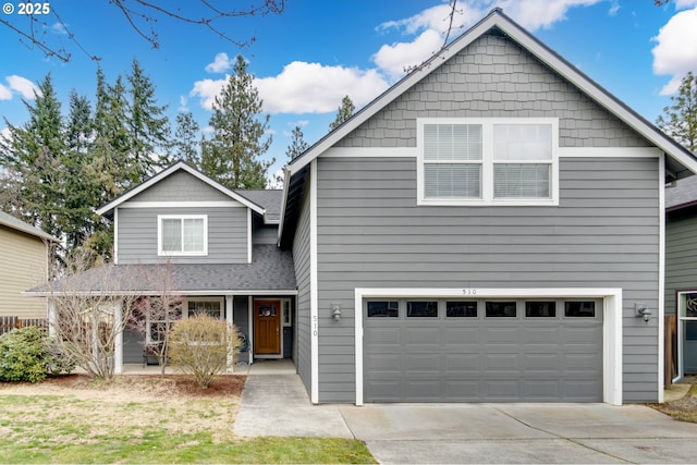 traditional home featuring an attached garage, a shingled roof, and concrete driveway