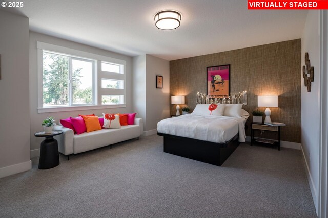 bedroom featuring an accent wall, carpet, and baseboards