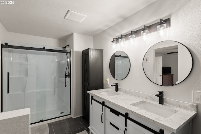 bathroom with a sink, double vanity, a shower stall, and tile patterned flooring