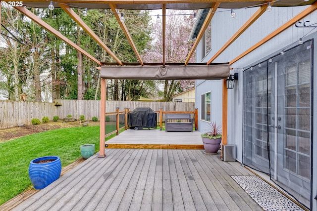 wooden deck featuring a yard, a fenced backyard, and a grill