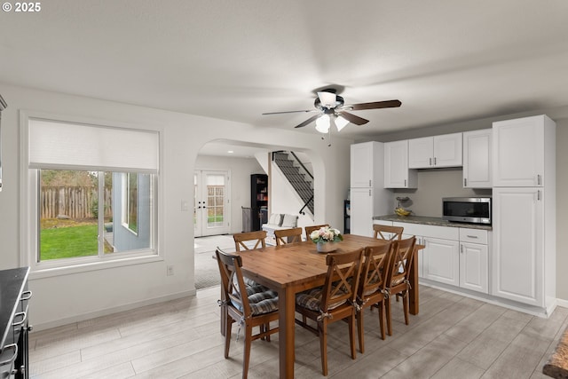 dining room with arched walkways, stairs, baseboards, and wood tiled floor