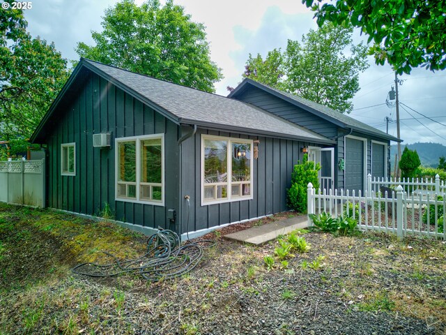 596 Sable Dr, Roseburg, OR 97470 - view of side of home featuring board and batten siding, fence, a shingled roof, and a wall unit AC