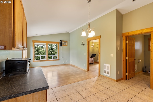 596 Sable Dr, Roseburg, OR 97470 - kitchen with vaulted ceiling, a chandelier, a wood stove, brown cabinetry, and dark countertops
