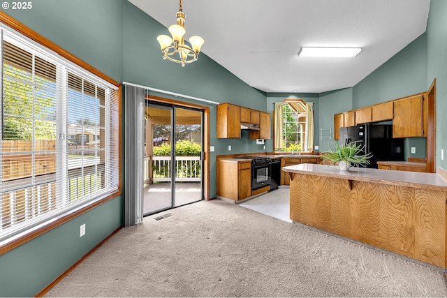 kitchen with a notable chandelier, black appliances, vaulted ceiling, a peninsula, and light colored carpet