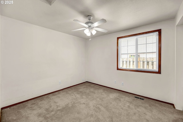 carpeted spare room featuring baseboards, visible vents, and a ceiling fan