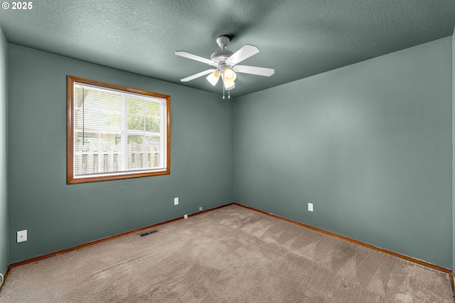 carpeted empty room featuring baseboards, visible vents, a ceiling fan, and a textured ceiling