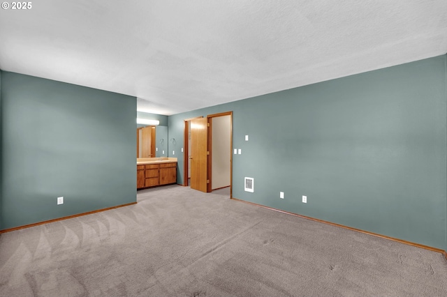 interior space with connected bathroom, visible vents, light carpet, and baseboards