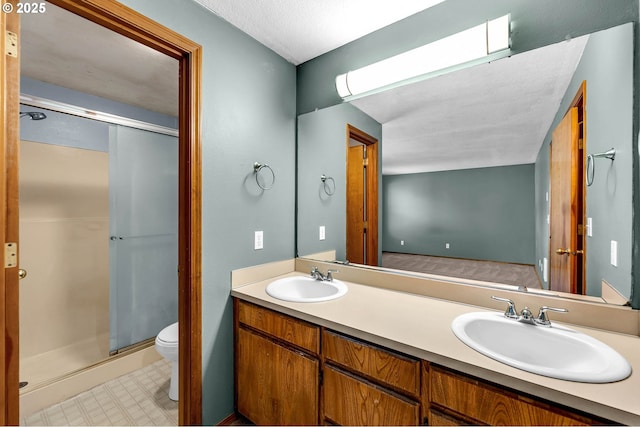full bathroom with double vanity, toilet, a shower stall, and a sink