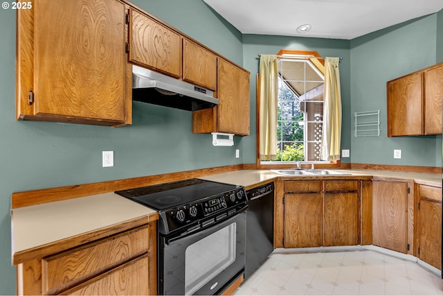 kitchen with brown cabinetry, under cabinet range hood, light countertops, black appliances, and a sink