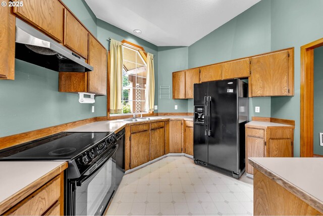 kitchen with black appliances, a sink, under cabinet range hood, and light countertops