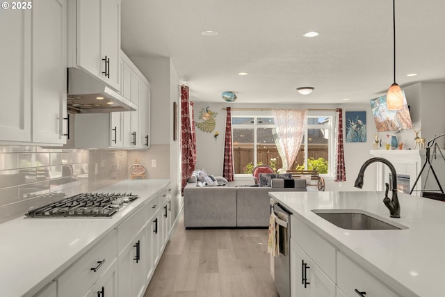 kitchen with pendant lighting, decorative backsplash, sink, stainless steel appliances, and white cabinets