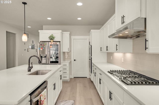 kitchen featuring stainless steel appliances, backsplash, decorative light fixtures, and sink