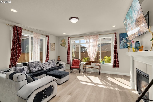 living room with a tiled fireplace and light hardwood / wood-style flooring