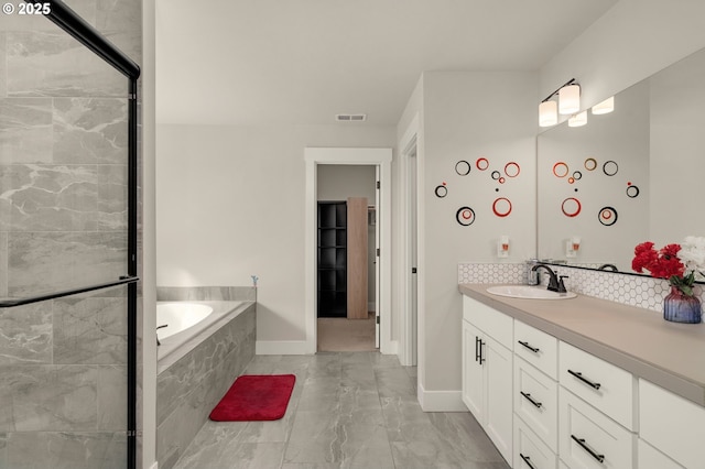 bathroom with vanity and tiled tub