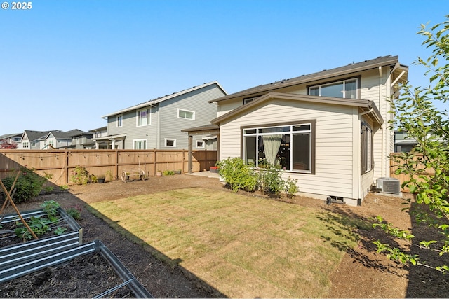 back of property with central AC unit and a yard