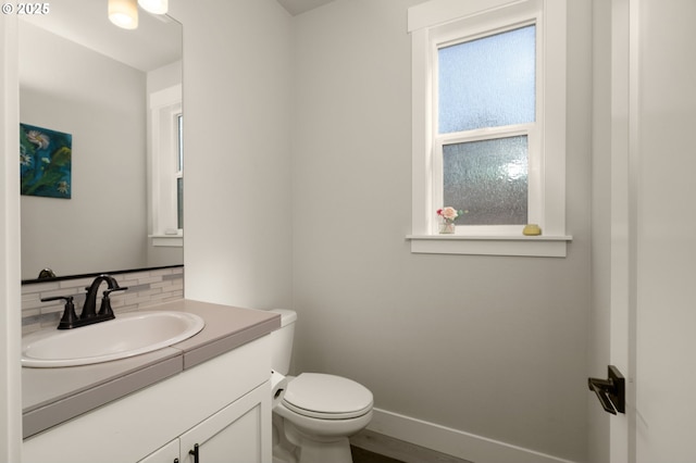 bathroom featuring backsplash, toilet, vanity, and a wealth of natural light