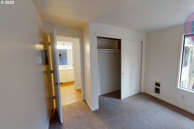 unfurnished bedroom with multiple windows, heating unit, light colored carpet, and a textured ceiling