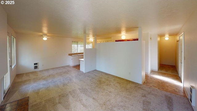 unfurnished living room featuring light carpet, heating unit, and a textured ceiling