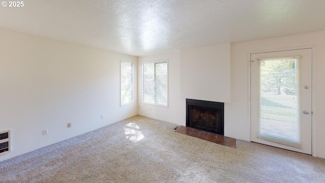 unfurnished living room featuring plenty of natural light, carpet flooring, and a textured ceiling