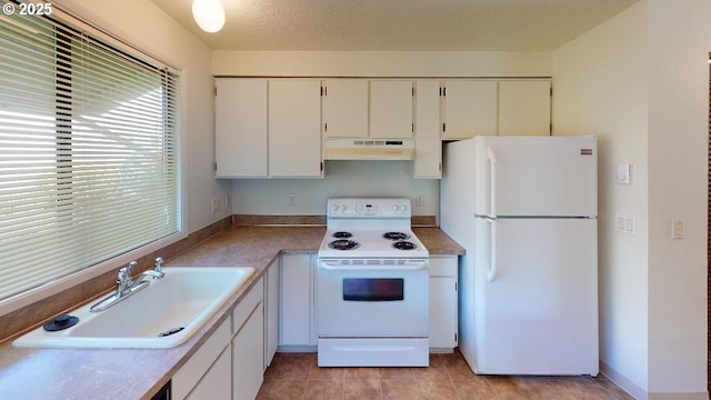 kitchen with sink, white appliances, a textured ceiling, white cabinets, and light tile patterned flooring