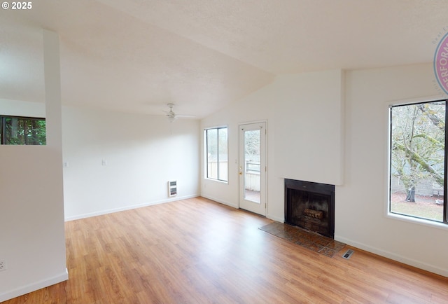 unfurnished living room with ceiling fan, vaulted ceiling, heating unit, and light wood-type flooring