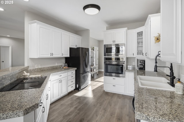 kitchen with sink, light wood-type flooring, white cabinets, and appliances with stainless steel finishes