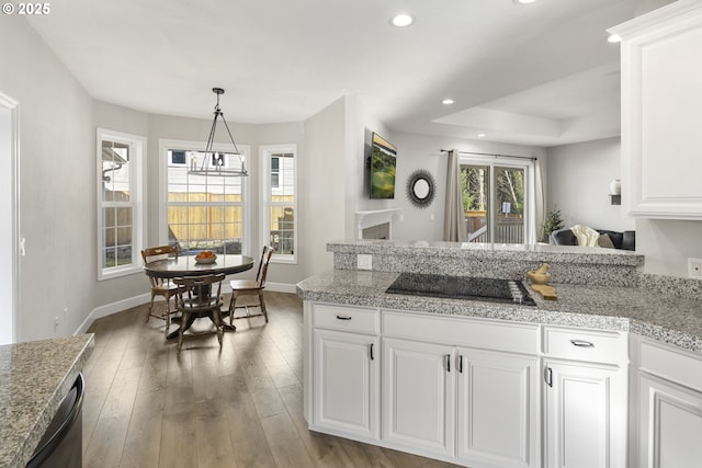 kitchen featuring pendant lighting, black electric stovetop, light hardwood / wood-style floors, white cabinets, and a raised ceiling