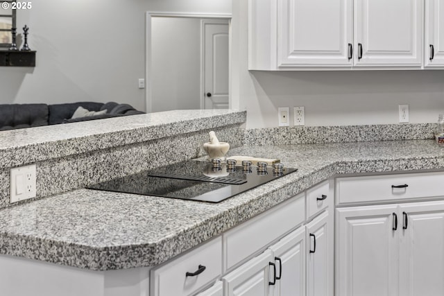 kitchen featuring black electric stovetop, white cabinets, and kitchen peninsula